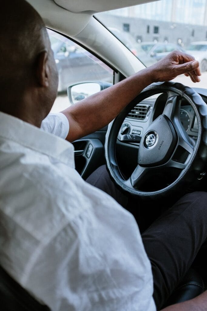 pexels-photo-4606346 A man driving a vehicle, highlighting the steering wheel and car interior.